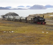 Old train in Ny-Ålesund, Spitsbergen/Svalbard. Kongsfjorden and it's massive glaciers in the background. (Wikimedia Commons)