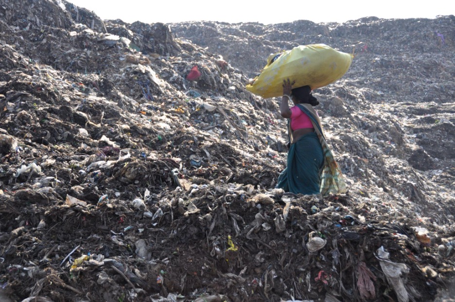 Waste picker of KKPKP with her sack of recyclables at the Uruli landfill, KKPKP.