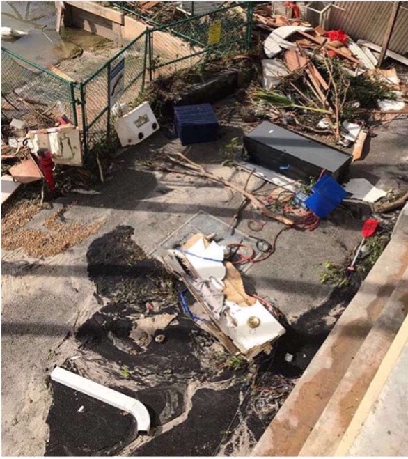 Destruction at my high school after Hurricane Irma. 
 This was taken looking into a back alleyway that is normally a road. You can see a file cabinet, a white rain gutter, a canoe paddle, and other assorted debris that was somehow blown into this area.