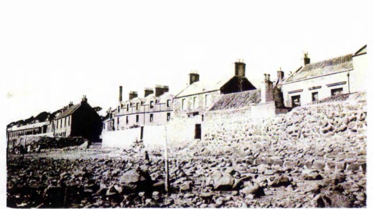 East Wemyss in 1924. The beach is made up of boulders and pebbles. To the far left of the photograph, steps lead down to the beach, and the people on the beach are dwarfed by the tall seawall behind - which appears to be over twice their height. From: Elisabeth Saiu, 'Mining subsidence: its effects on the south-east Fife coastline' (unpublished PhD dissertation, University of St Andrews, 1998, available at https://research-repository.st-andrews.ac.uk/handle/10023/15553 ).
