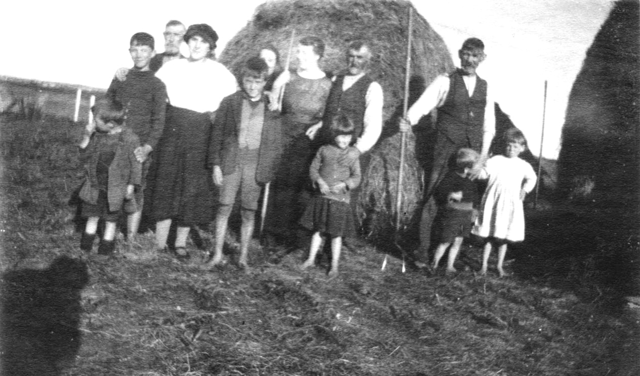 A crofting family in their stackyard in the east end of Tiree in the beginning of the 20th century. Note the pitchforks for tossing the hay up to the top of the stack. An Iodhlann. 